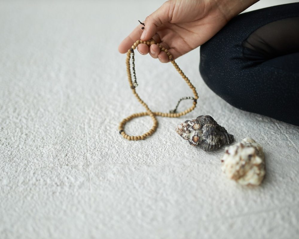 cropped-image-unrecognizable-woman-holding-mala-beads-prayer-meditation-keep-track-while-chanting-repeating-mantra-sitting-floor_343059-2123